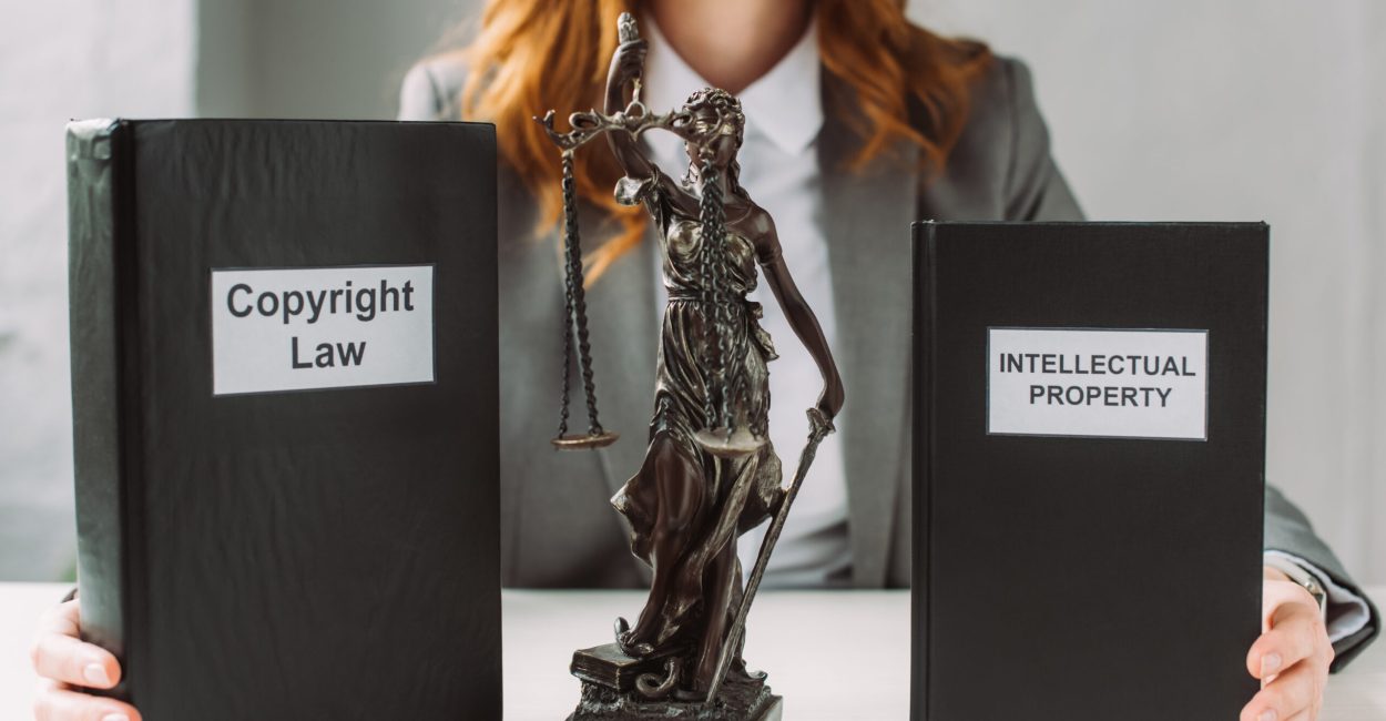 Cropped view of lawyer holding books with intellectual property and copyright law lettering near